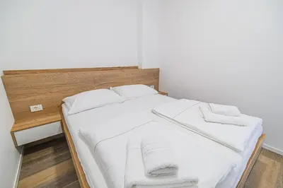 a bed with white sheets and a wooden headboard at Apartment Gorski Raj in Kranjska Gora