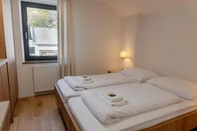 a bedroom with two beds with white sheets and a window at Hiša S'TJE Krvavec ski resort in Cerklje na Gorenjskem