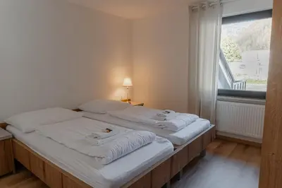 a bedroom with a bed with white sheets and a window at Hiša S'TJE Krvavec ski resort in Cerklje na Gorenjskem