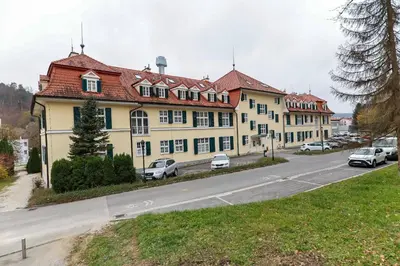 a large yellow building with cars parked on the side of a road at Apartments at Villa Golf in Rogaška Slatina