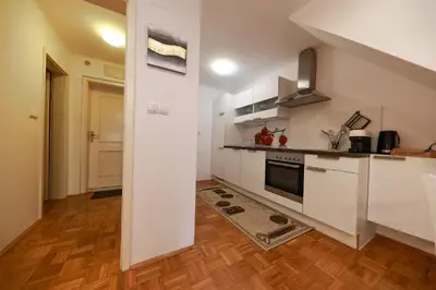 a kitchen with white cabinets and a wooden floor at Apartments at Villa Golf in Rogaška Slatina