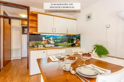 a kitchen with a wooden table and white cabinets at Apartma Planinski Raj in Zreče