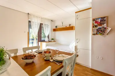a kitchen and dining room with a table and a bed at Apartma Planinski Raj in Zreče
