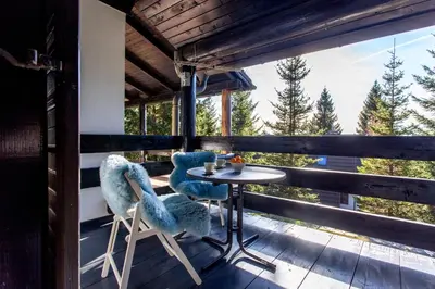 a porch with two chairs and a table on a deck at Apartma Planinski Raj in Zreče