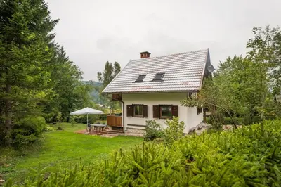 a small white house with a table and an umbrella at Chalet Ceri in Bohinj