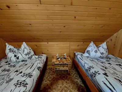 a room with two beds and a table in it at Koča Lipa pod Veliko planino in Luče