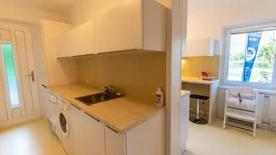 a kitchen with white cabinets and a sink and a desk at Lake Bled Apartments in Bled