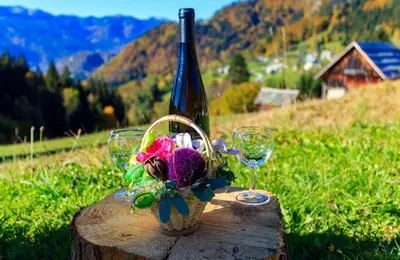 a bottle of wine and two wine glasses on a stump at Holiday house Pokrovec - Bohinj in Bohinj