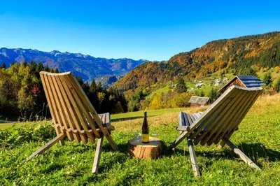 two chairs and a bottle of wine sitting on a hill at Holiday house Pokrovec - Bohinj in Bohinj