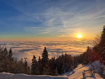a view of a snowy mountain with the sun above the clouds at Apartma Maya in Cerklje na Gorenjskem