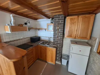 a small kitchen with wooden cabinets and a white refrigerator at Apartma Maya in Cerklje na Gorenjskem