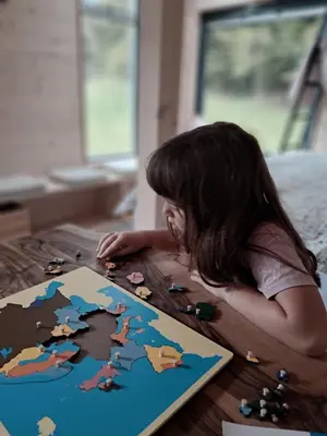 a little girl laying on a table playing with a puzzle at Posestvo Brida - Glamping in Ilirska Bistrica