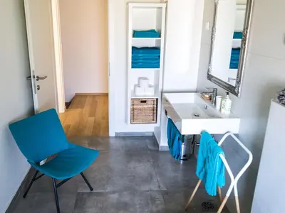 a bathroom with a blue chair and a sink at A modern flat in Kranjska Gora