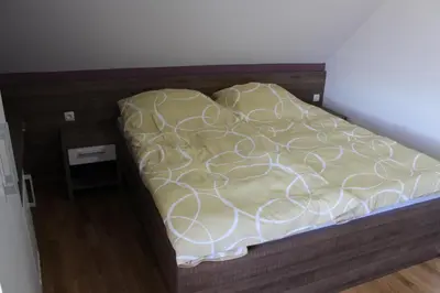 an unmade bed with a wooden frame in a bedroom at Hiša nasprot Sonca in Črnomelj