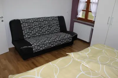 a black chair sitting in a room with a rug at Hiša nasprot Sonca in Črnomelj