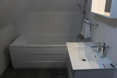 a white bathroom with a sink and a bath tub at Hiša nasprot Sonca in Črnomelj