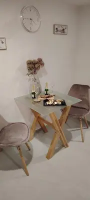 a table with two chairs and a clock on the wall at Mini wellness studio-near the airport in Smlednik