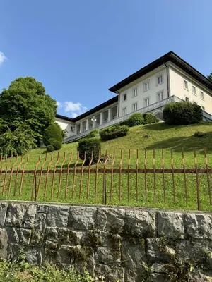 a house on top of a hill with a fence at Blue Sky Apartment in Bled