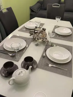 a table with plates and cups and utensils on it at Blue Sky Apartment in Bled