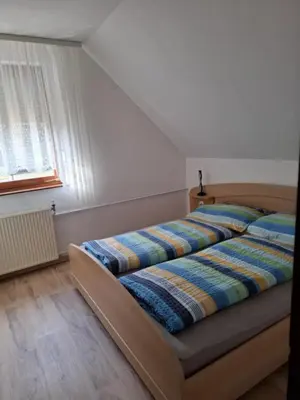 a bedroom with a bed with a striped blanket on it at Apartmaji PRI JUNESKO in Kranjska Gora