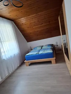 a bedroom with a blue bed and a wooden ceiling at Apartmaji PRI JUNESKO in Kranjska Gora