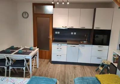 a kitchen with white cabinets and a table and a table and chairs at Apartment Misty Forest in Kranjska Gora