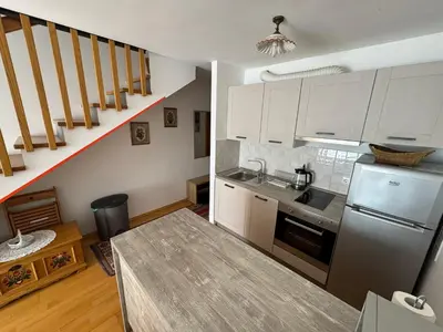 a kitchen with white cabinets and a kitchen table at Apartment MANCA-HOLIN in Bohinj