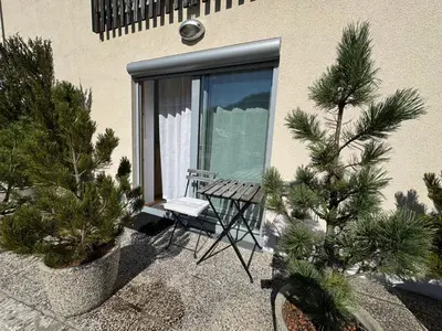a table and chair sitting outside of a window with trees at Apartment MANCA-HOLIN in Bohinj