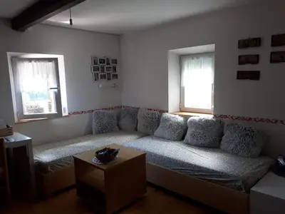 a living room with a couch and two windows at Cottage Stela Bohinj in Bohinj