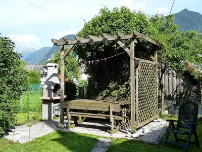 a wooden pergola with a bench in a garden at Chalet Bovec in Bovec