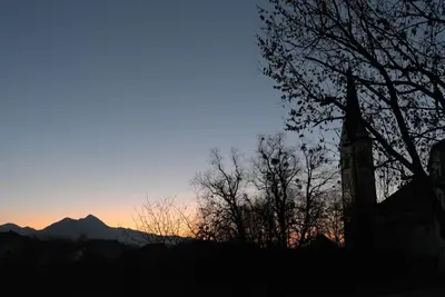 a sunset with trees and mountains in the background at Hiša Linhart Apartment in Radovljica