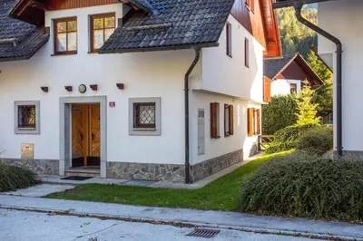 a house with a wooden door in a yard at Apartmaji Potepuh in Kranjska Gora
