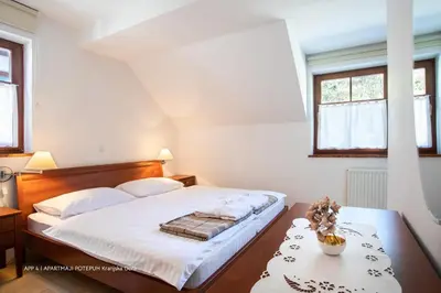 a bedroom with a bed with a table and two windows at Apartmaji Potepuh in Kranjska Gora