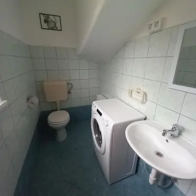 a white bathroom with a sink and a toilet at Apartma pri Milki in Cerkno
