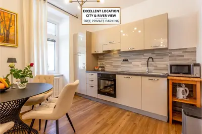 a kitchen with white cabinets and a table with chairs at Apartma Apolon II in Krško