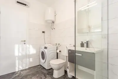 a white bathroom with a toilet and a sink at Apartma Apolon II in Krško