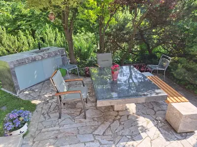 a stone patio with a glass table and chairs at Pohorje Zen Garden in Pohorje