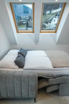 a bed in a room with two windows at Apartma pri Hrvatu in Bohinj