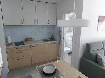 a kitchen with white cabinets and a table and a couch at Bohinj Jeglič C17 in Bohinj