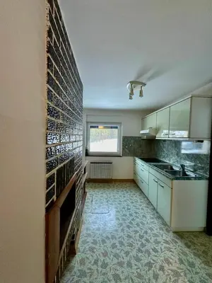 a kitchen with white cabinets and a tile wall at Apartment River in Vitanje