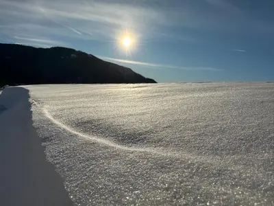 a snow covered field with the sun in the sky at Apartment River in Vitanje
