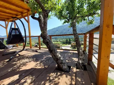 a tree on the deck of a house with a view at Apartments Denis in Tolmin