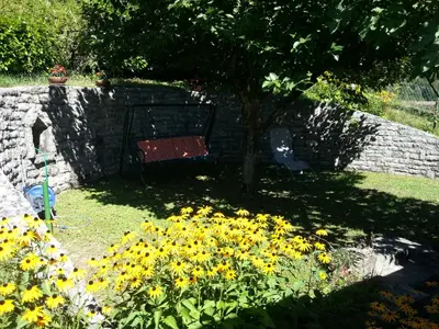 a garden with yellow flowers and a red bench at Apartments Denis in Tolmin