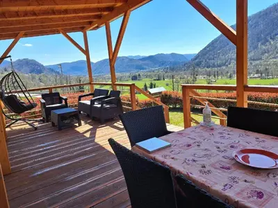 a wooden deck with a table and chairs and a swing at Apartments Denis in Tolmin