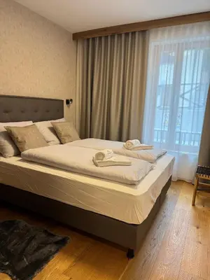 a large bed in a bedroom with a large window at Steblaj apartments Park in Kranjska Gora