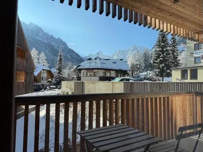 a balcony with a bench and a snow covered mountain at Steblaj apartments Park in Kranjska Gora