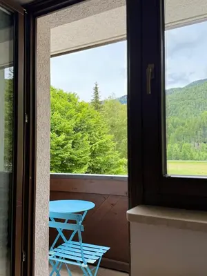 a table and a chair on a balcony with a window at Lotti's Apartment in Kranjska Gora