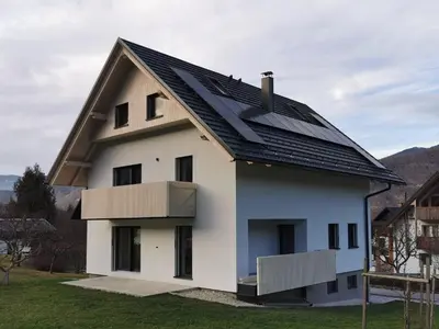 a large white house with a black roof at Vila Perunika in Bohinj