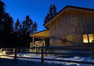 a log cabin in the snow at night at Gorska koča Krvavec in Cerklje na Gorenjskem