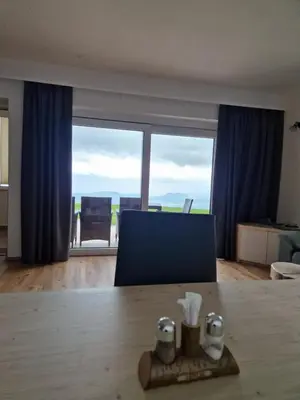 a living room with a table and a large window at Apartmaji Pr Ambružarju in Cerklje na Gorenjskem